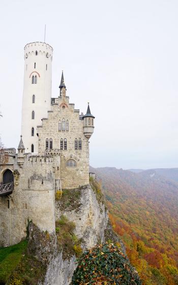 A fairytale-esque castle on a clifftop overlooks the changing fall leaves 